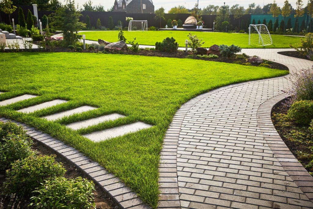 Landscaping of the garden. path curving through Lawn with green grass and walkway tiles